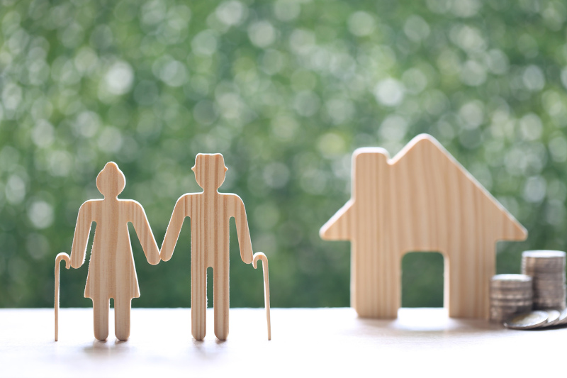 elderly couple with model house and stack of coins - consider costs